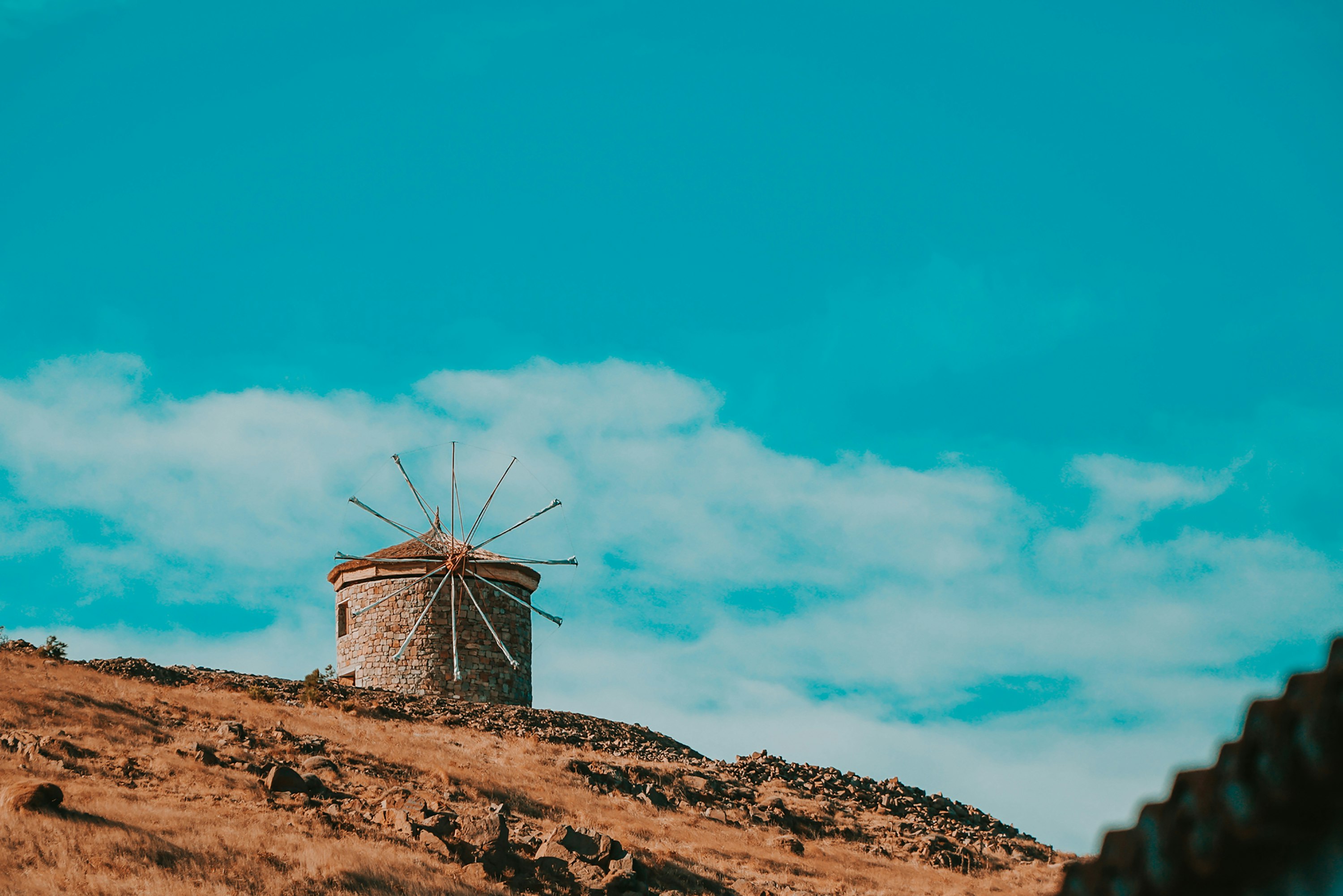 brown wooden windmill on brown field under blue sky during daytime